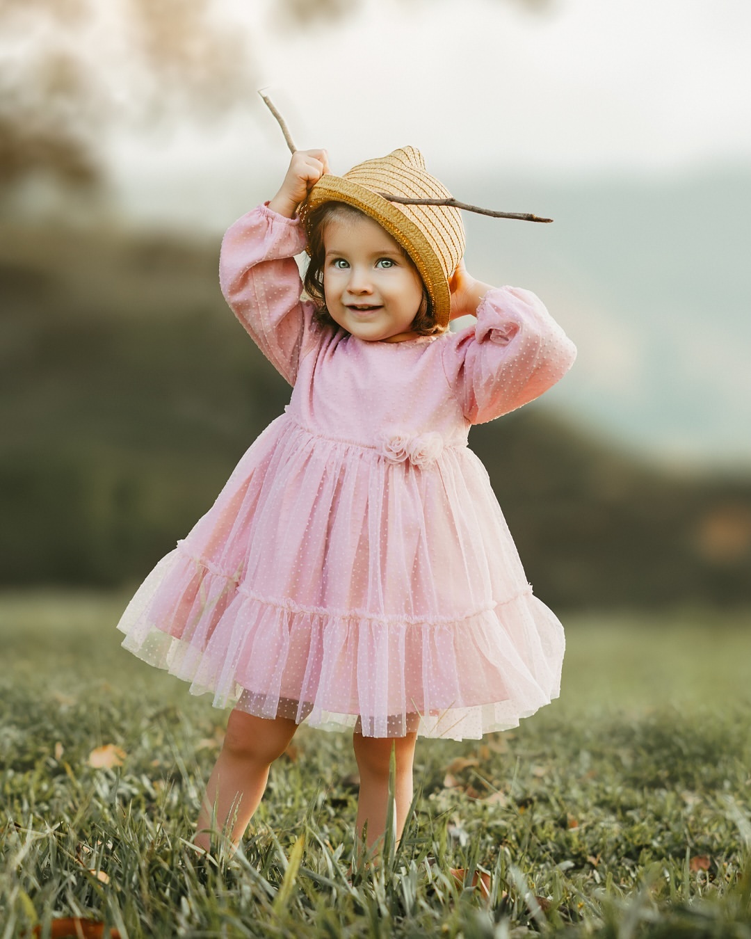 Niña con vestido rosa jugando en el campo
